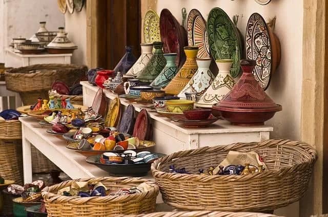 Stragan z kolorową marokańską ceramiką: talerze, tadżiny i misy w koszach na suku w Tangerze