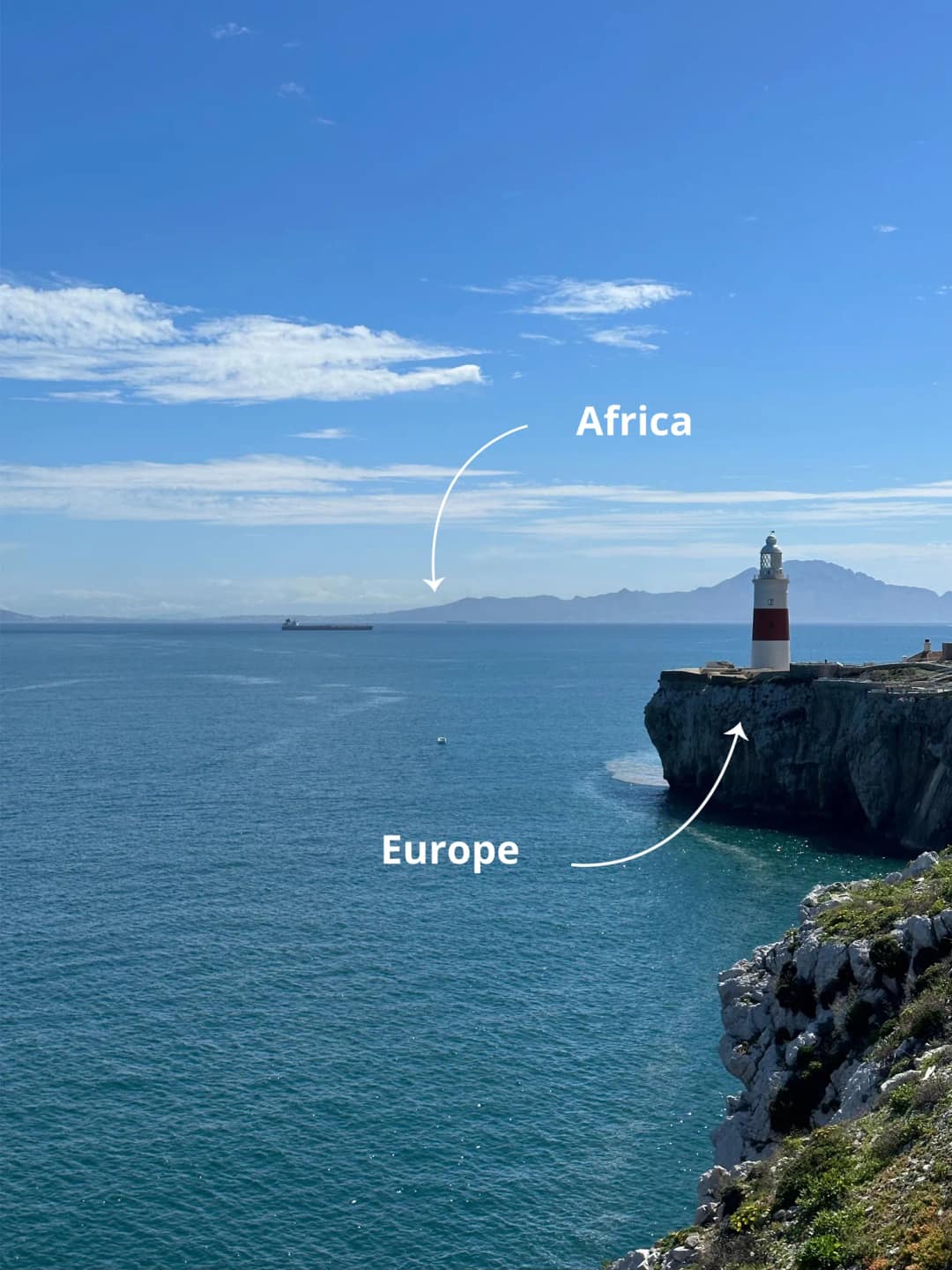 Latarnia morska na Punkcie Europa z widokiem przez cieśninę na góry Afryki, z podpisami Europe i Africa