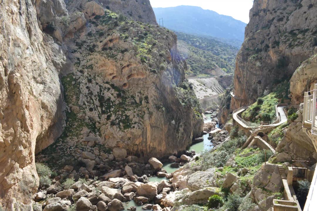 Kładki Caminito del Rey nad turkusową rzeką Guadalhorce w południowym wąwozie, w oddali schody