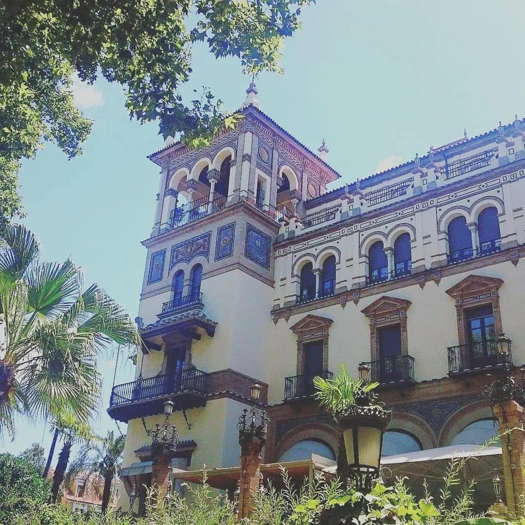 Wieża i fasada hotelu Alfonso XIII w Sewilli z azulejos, widziane spod palm
