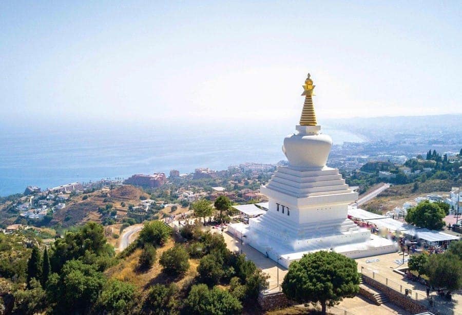 Biała buddyjska stupa z złotym szczytem na wzgórzu w Benalmádenie z widokiem na Costa del Sol i morze